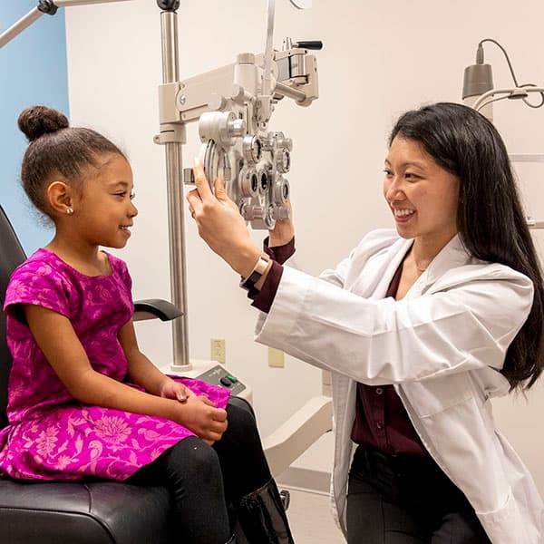 An UMSL student optometrist conducts an eye exam for a young girl in a clinical setting.